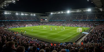 Premier League stadium at night, packed with fans, dynamic action on the pitch