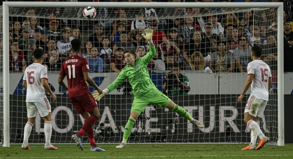 Goalkeeper executing a dramatic, game-saving dive to block a shot in a critical MLS playoff moment.